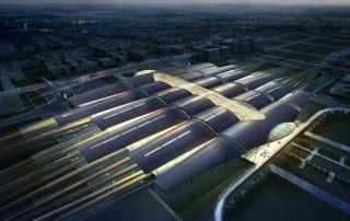 Aerial view of Manchester Airport's modern terminal with curved glass roofs at dusk.
