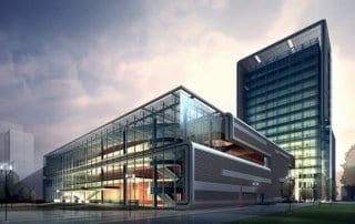 Modern glass and steel building near Manchester Airport with surrounding trees.